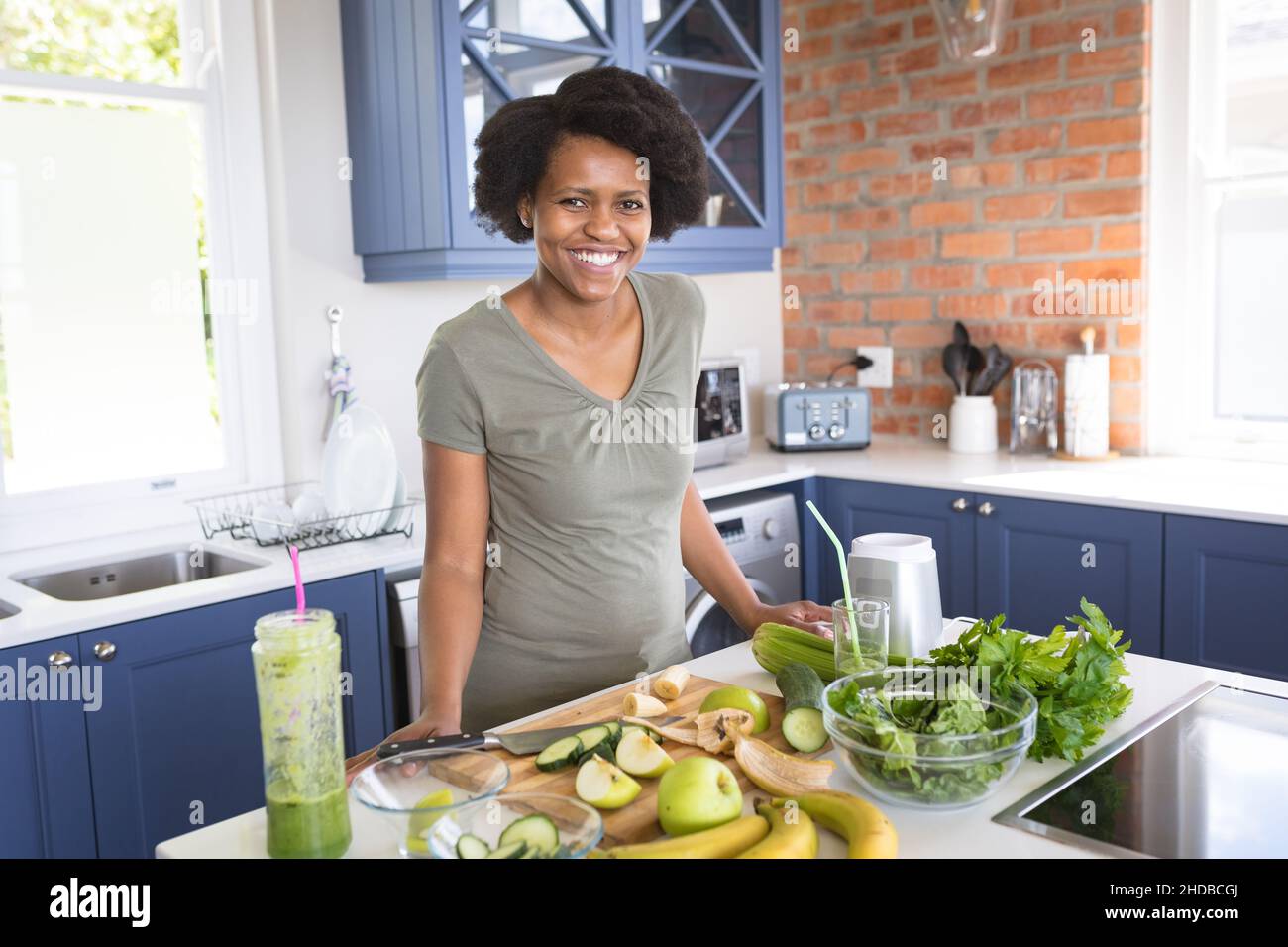 Portrait d'une femme afro-américaine heureuse avec des fruits et des légumes sur l'île de cuisine à la maison Banque D'Images
