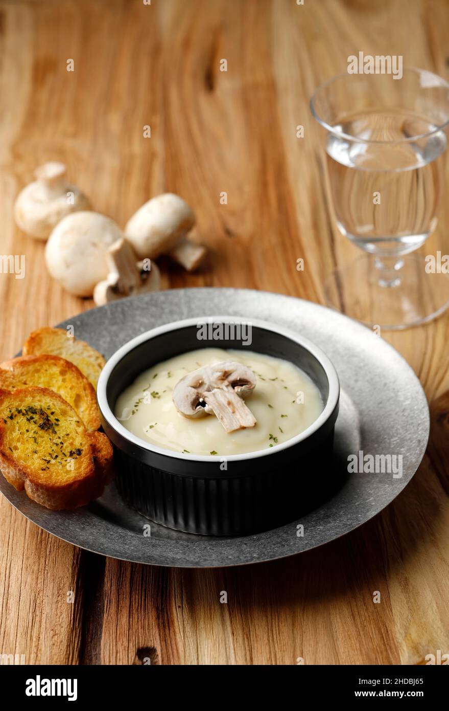 Soupe à la crème de champignons avec pain à l'ail croustillant sur table en bois Banque D'Images