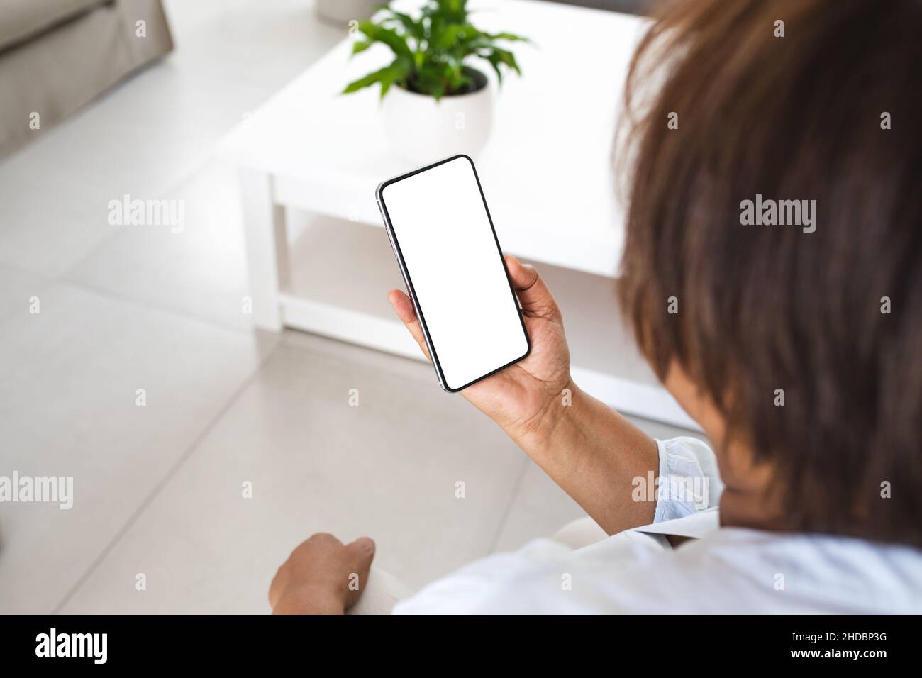 Femme âgée utilisant un smartphone avec un espace de copie dans le salon à la maison Banque D'Images