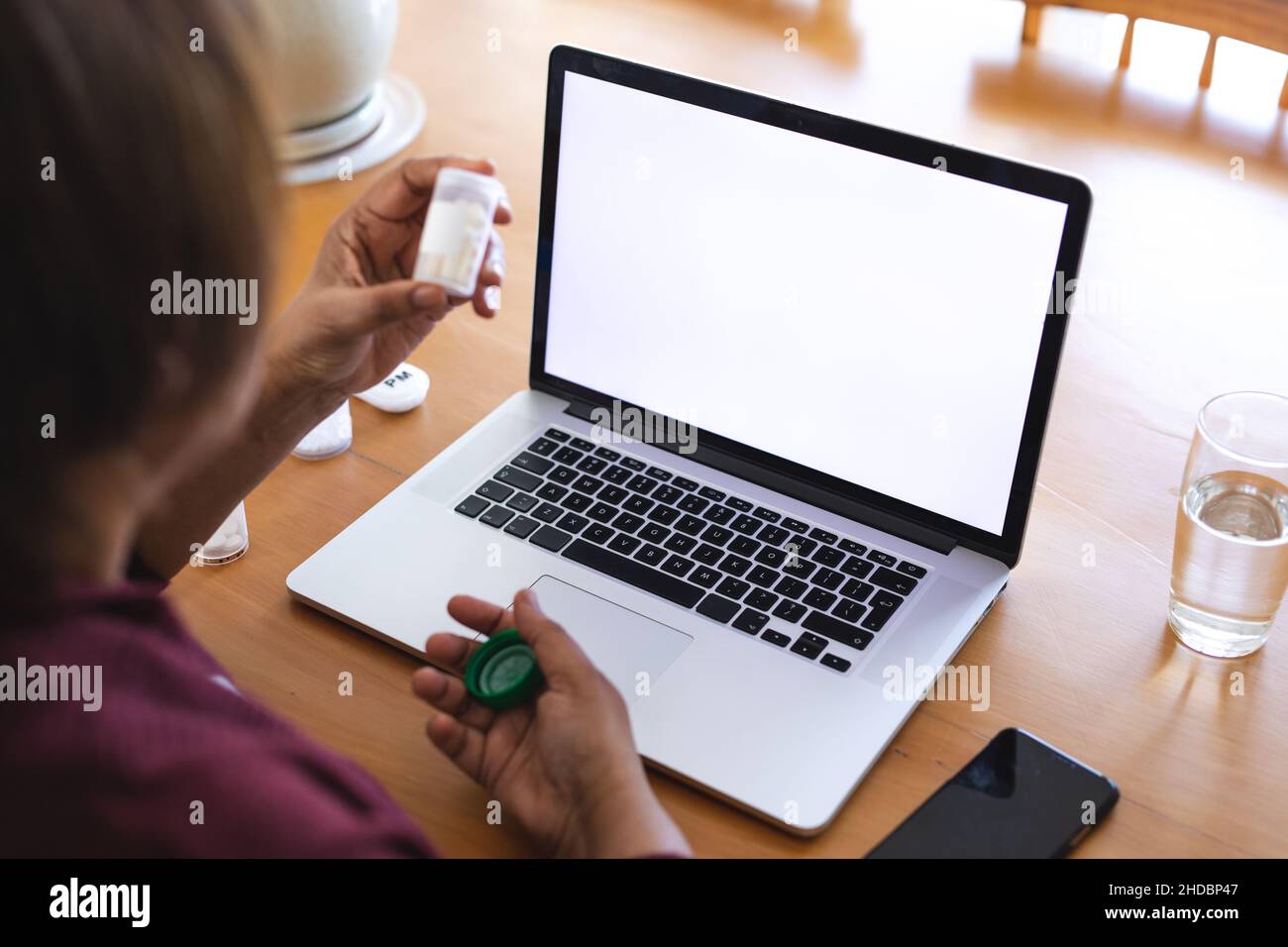 Femme âgée avec des médicaments utilisant un ordinateur portable pendant la consultation en ligne du médecin à la maison, espace de copie Banque D'Images
