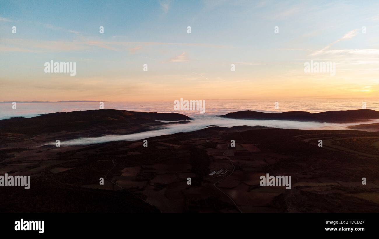 Vue aérienne d'une mer de nuages entre les montagnes au coucher du soleil Banque D'Images