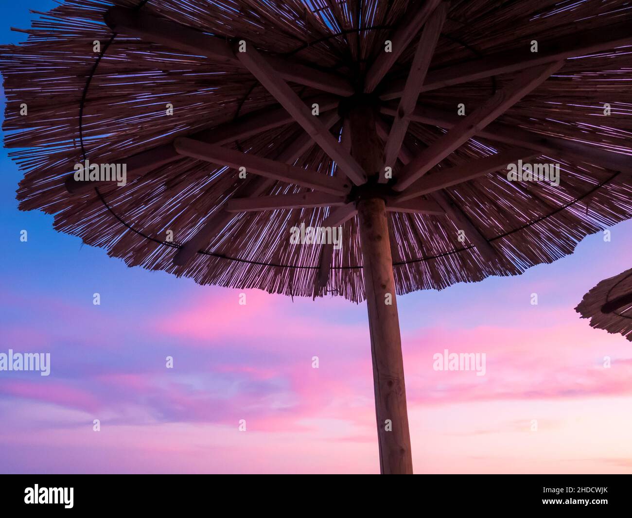 Parasol de plage, vue sur le magnifique coucher de soleil bleu et violet, ciel et parasol de plage de paille.Idéal pour les vacances.Voyages et vacances.Plage sur Vir Banque D'Images