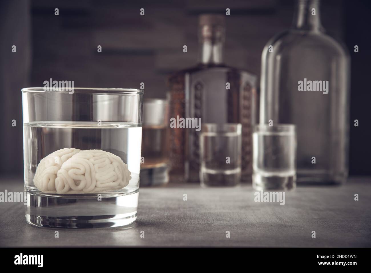 Modèle de cerveau humain dans un verre avec une boisson alcoolisée, sur fond de bouteilles avec de l'alcool.Dépendance à l'alcool.Dommages causés par l'alcool au cerveau. Banque D'Images