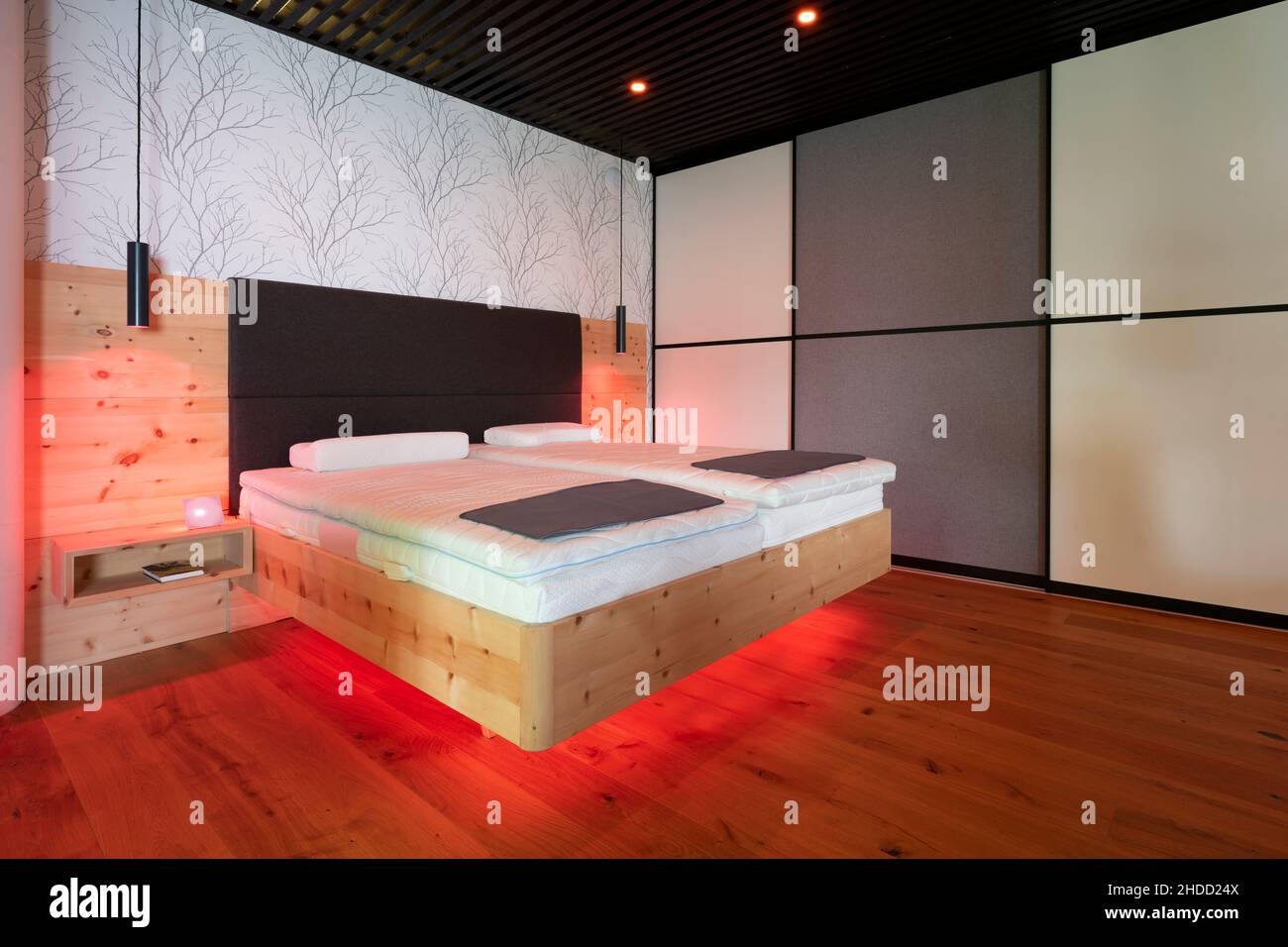 lit moderne en pin de pierre avec éclairage led, lampes suspendues et plafond à lamelles noires Banque D'Images