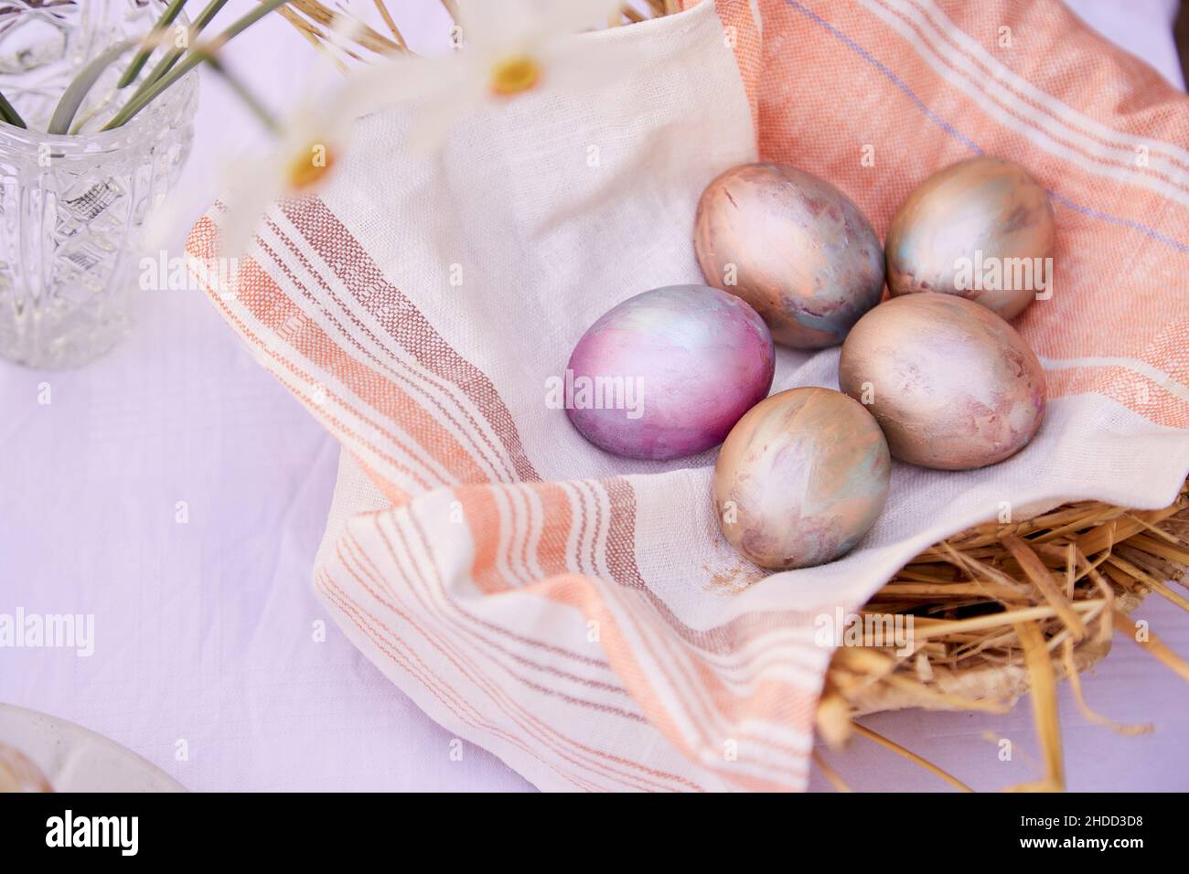 Œufs de Pâques dans un panier en osier.Veri peri et œufs multicolores orange et fleurs de narcisse.Vue de dessus, espace de copie. Banque D'Images