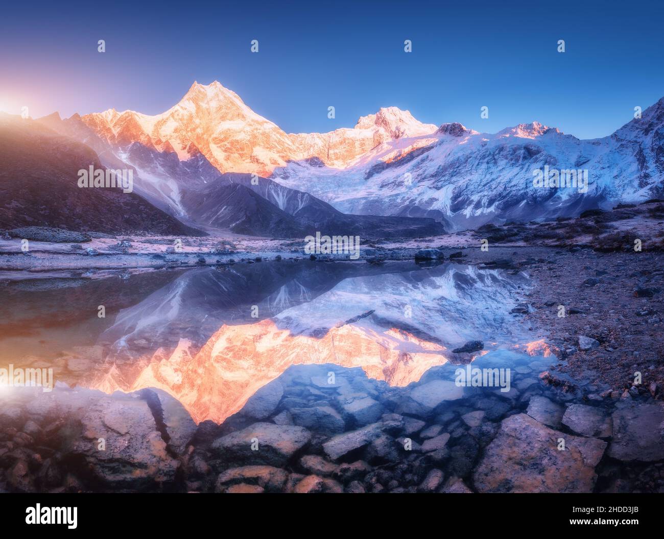 Montagne enneigée avec des sommets éclairés et un lac magnifique Banque D'Images