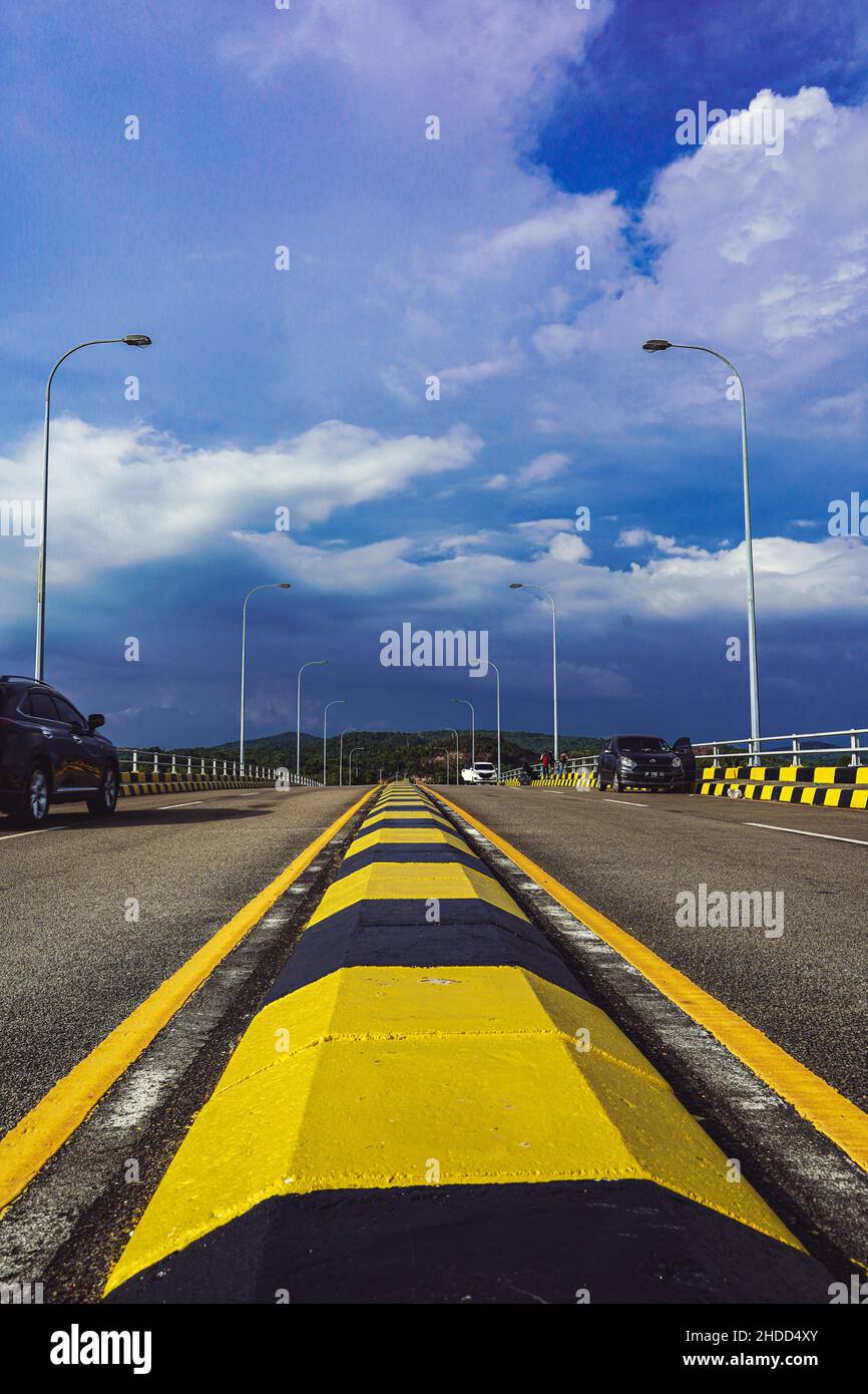 Vue sur le panneau jaune-noir de la route du pont de l'île de Batam, Indonésie avec un ciel bleu nuageux Banque D'Images