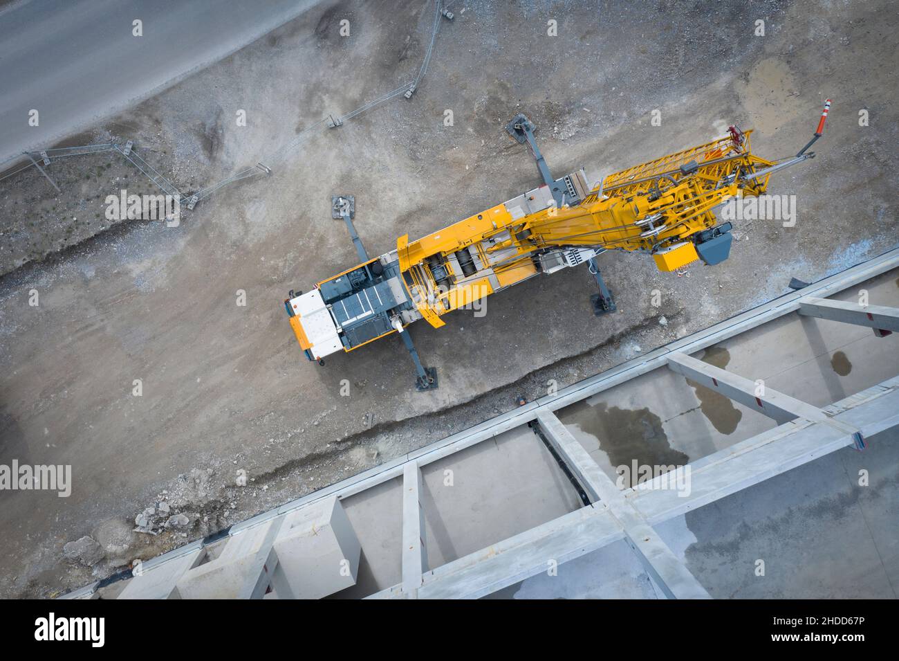 Vue d'en haut sur une grande grue de camion lourd devant un échafaudage en béton d'un hall industriel Banque D'Images