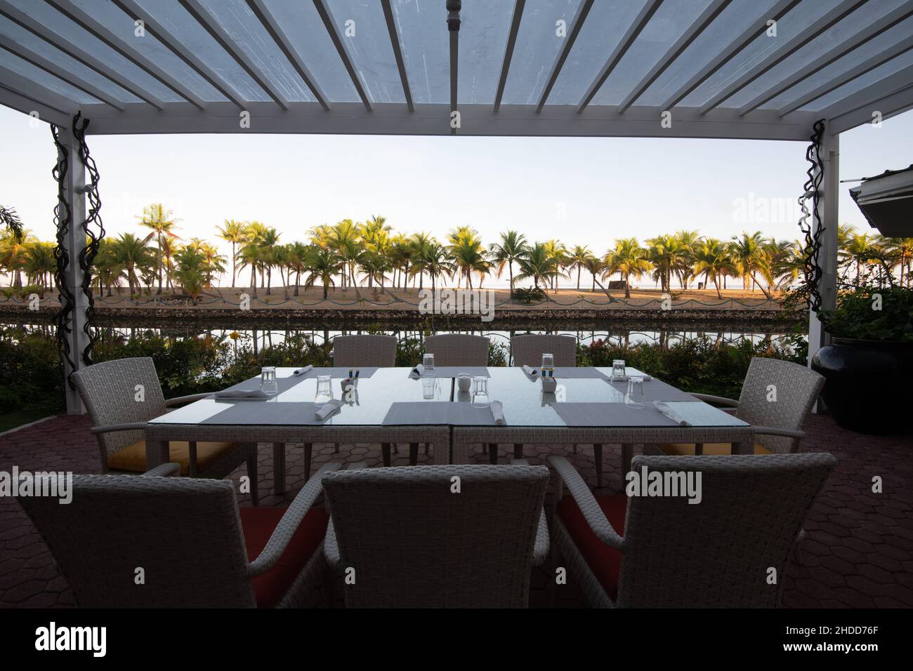 Une table sous l'abri avec vue sur une plage ensoleillée avec des palmiers Banque D'Images