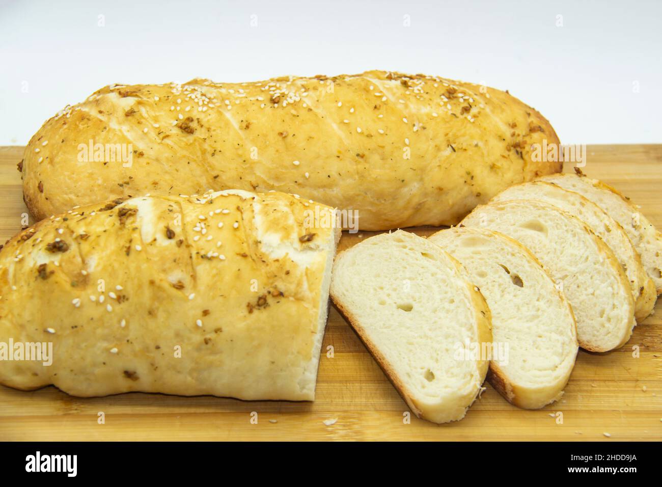 Pain de blé cuit à la farine à la maison.Tranché du pain sur une planche de bois contre le fond.Nourriture sans OGM.Pain fait maison avec épices dessus. Banque D'Images