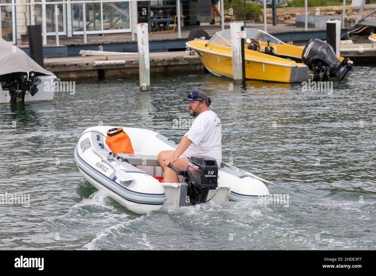 Homme dans un canot pneumatique dirige le bateau vers la rive avec le timon sur l'extérieur, Sydney, Australie Banque D'Images