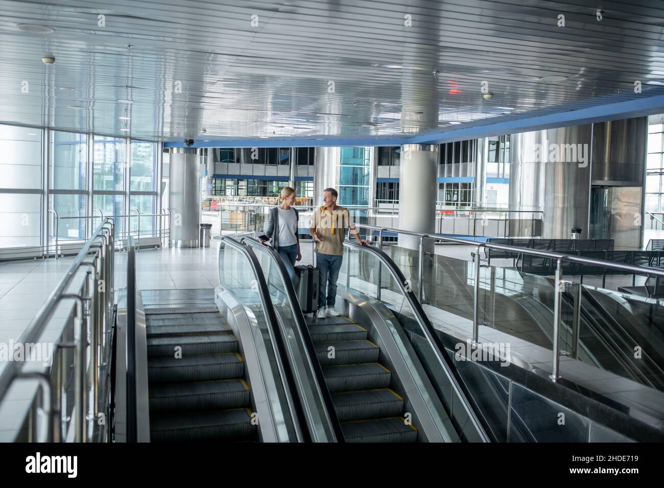 Deux passagers de l'aéroport ayant une conversation sur l'escalier roulant Banque D'Images