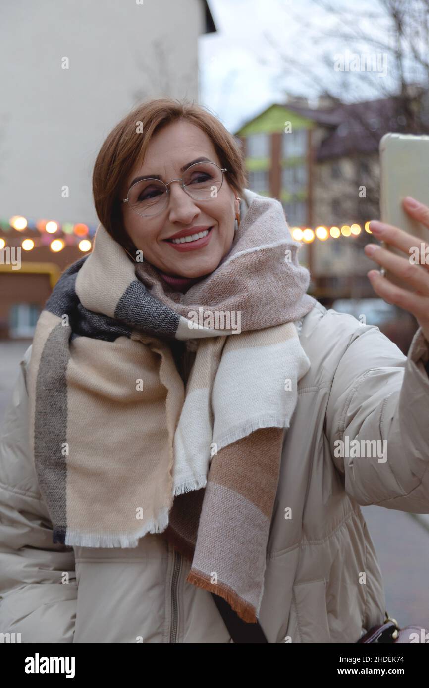 Belle jeune femme d'âge moyen fait selfie sur smartphone dans la rue. Banque D'Images