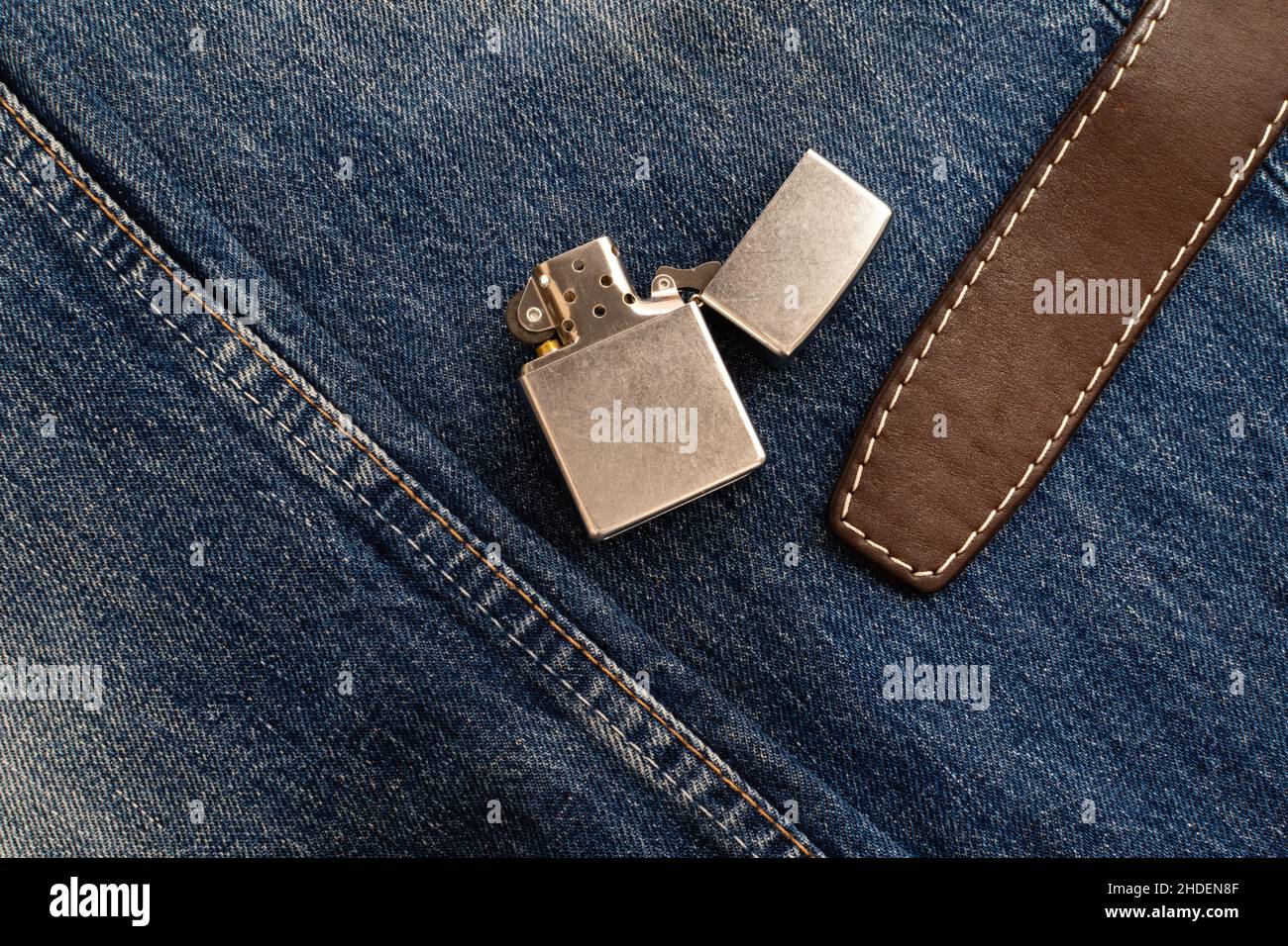 Briquet en métal vintage et ceinture en cuir sur le denim avec double couture Banque D'Images
