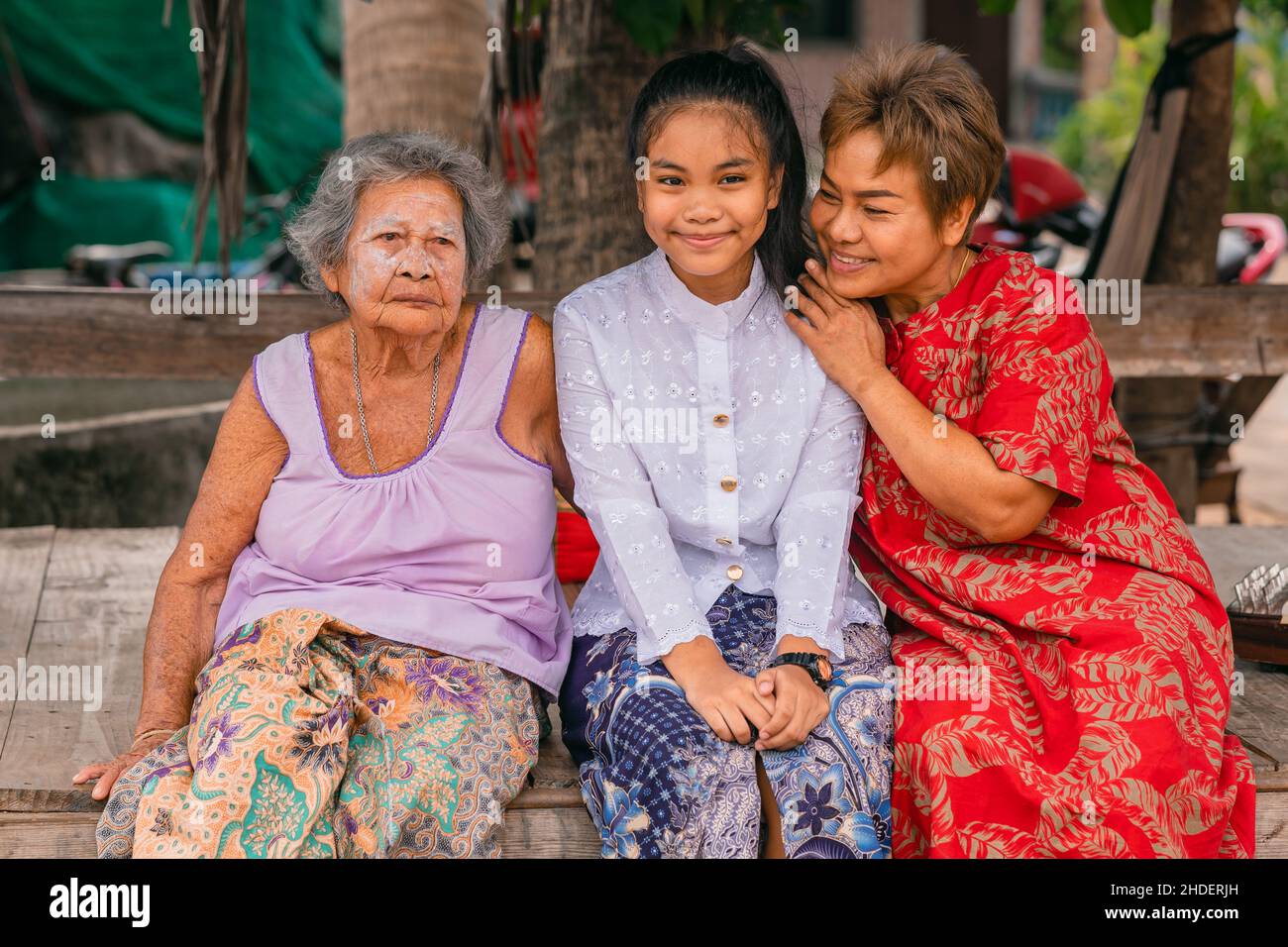 Joyeux asiatique féminin trois générations de petite-fille, fille avec grand-mère souriant et assis ensemble à l'extérieur.Mère embrassant sa fille. Banque D'Images