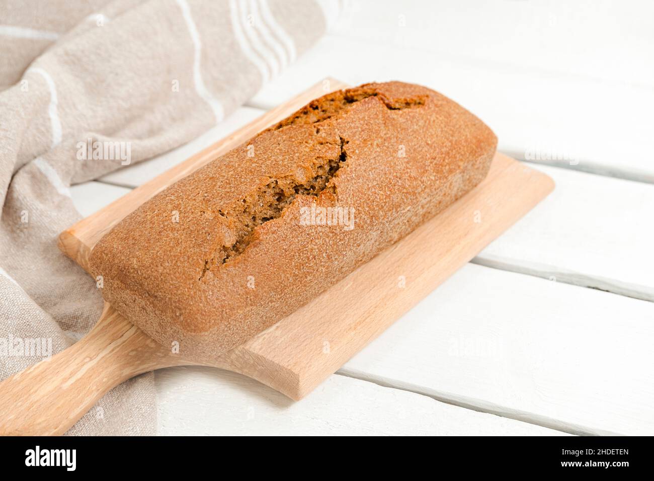 Tranches de pain au levain maison sur planche à découper en bois sur table blanche, mise au point sélective Banque D'Images