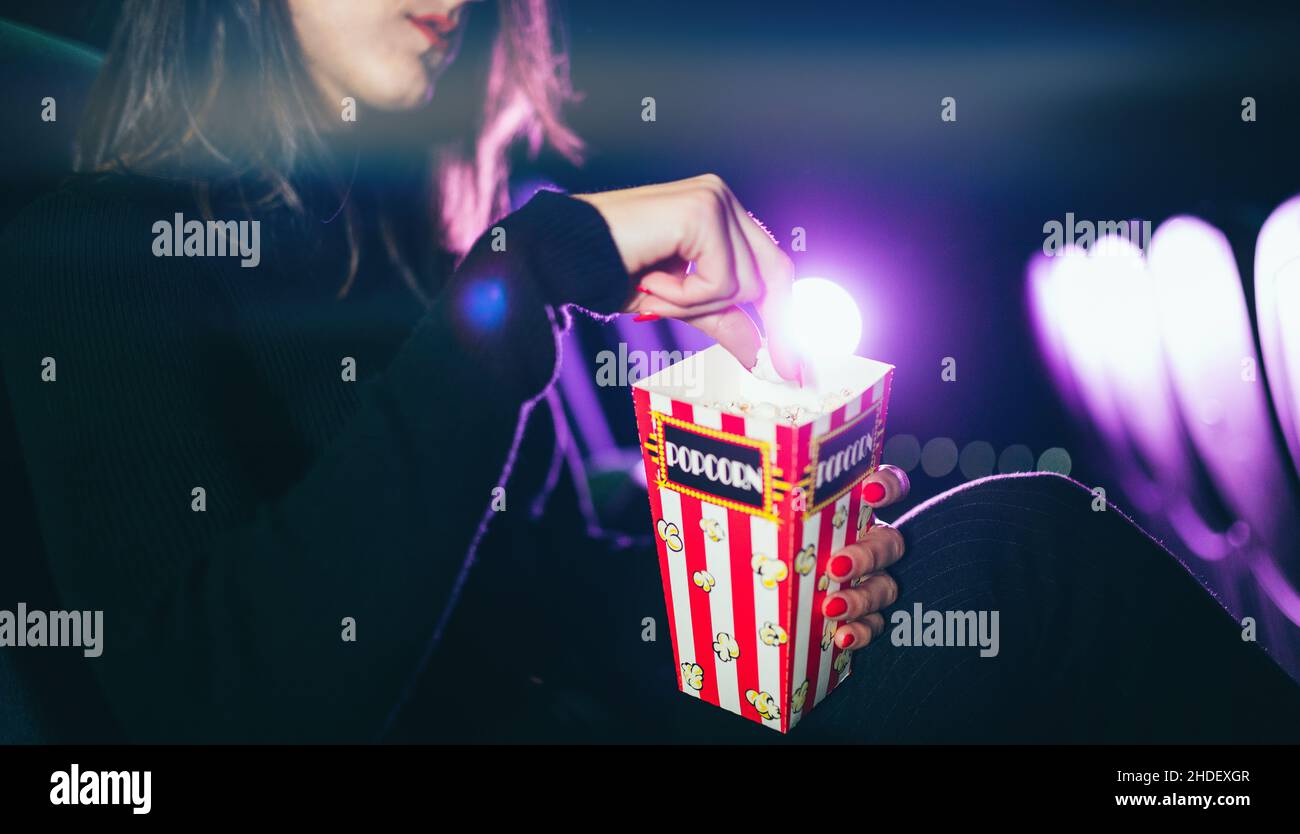 une jeune fille assise au cinéma mange du maïs pop Banque D'Images
