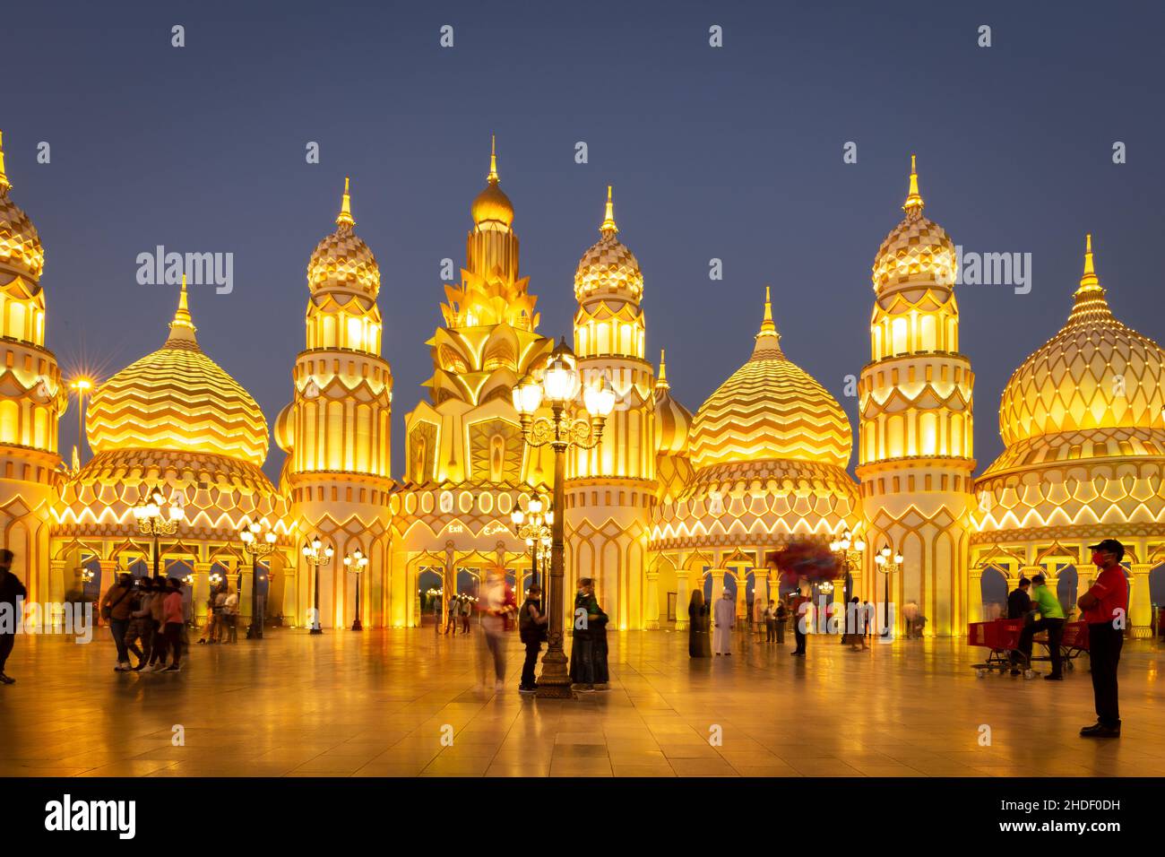Dubaï, Émirats arabes Unis, 10.01.21.Parc d'attractions Global Village la nuit avec tours et dômes de style arabe illuminés jaunes et personnes marchant. Banque D'Images