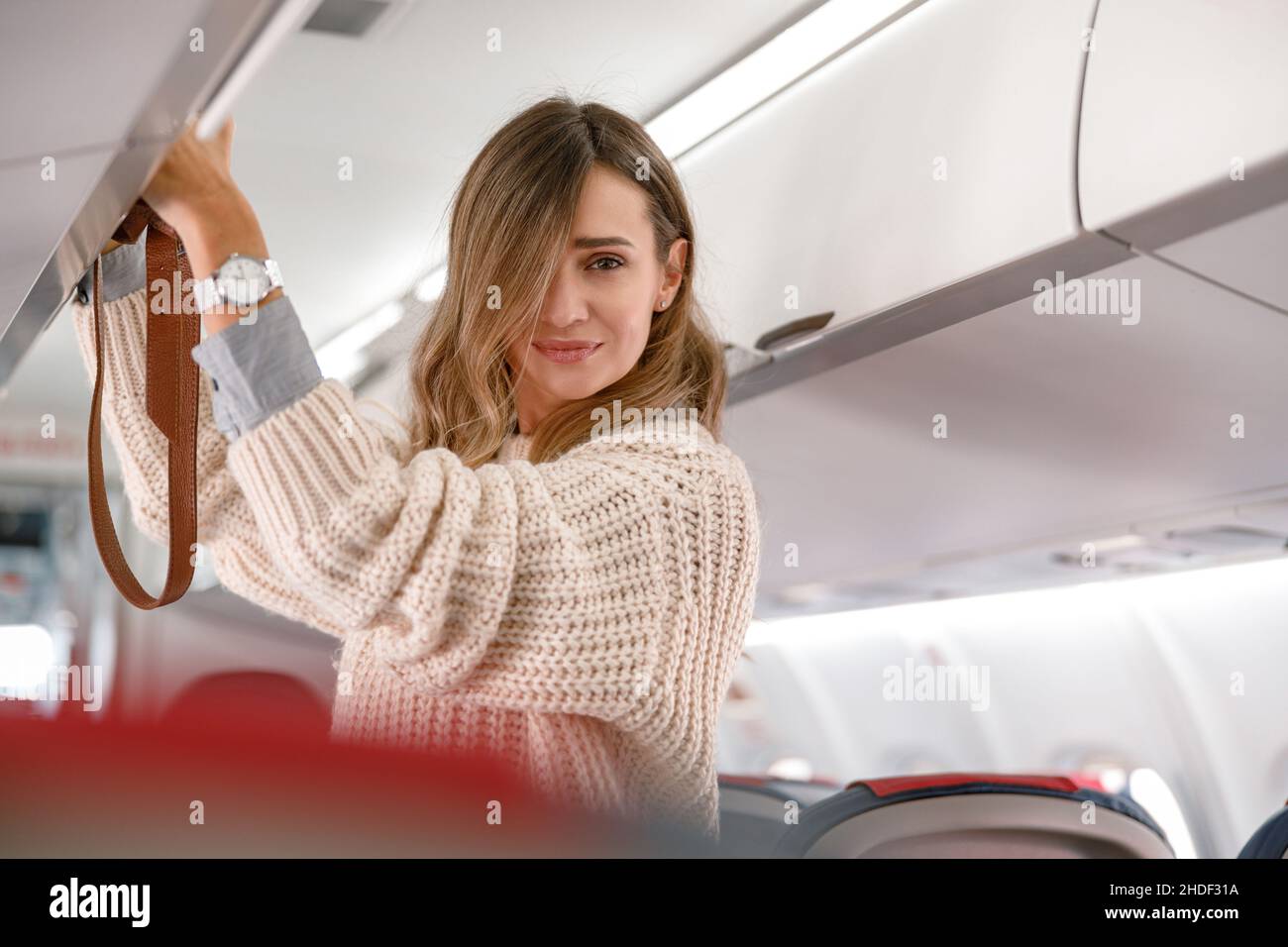 Femme mettant le sac dans le coffre à bagages au-dessus de l'avion Banque D'Images