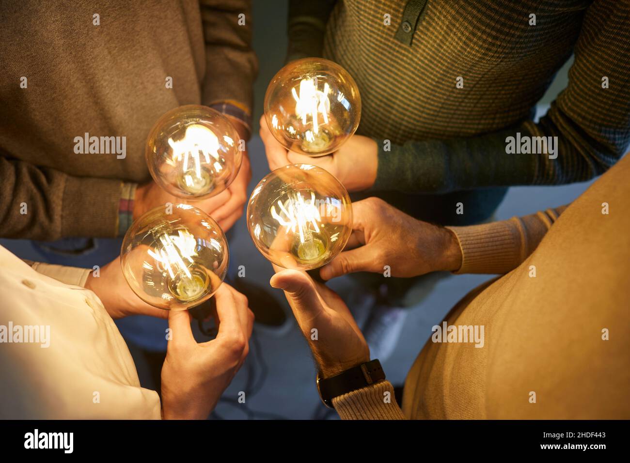 Équipe de personnes tenant des ampoules lumineuses comme symbole d'idées créatives et d'innovations Banque D'Images