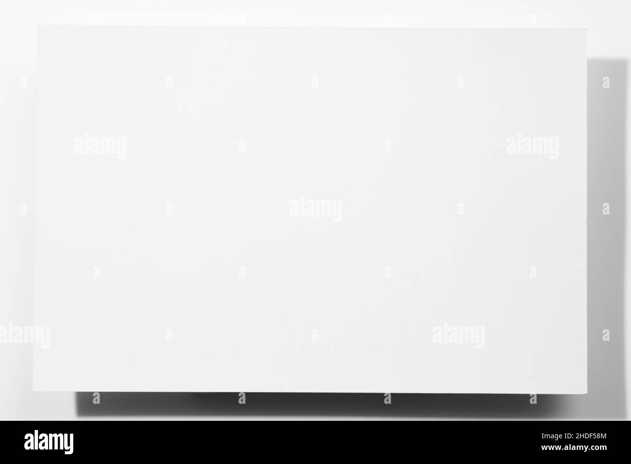 Grande feuille de papier blanc en carton vierge de couleur - bannière de forme rectangulaire avec des ombres tombant sur fond blanc.Maquette de carte.Copier l'espace Banque D'Images