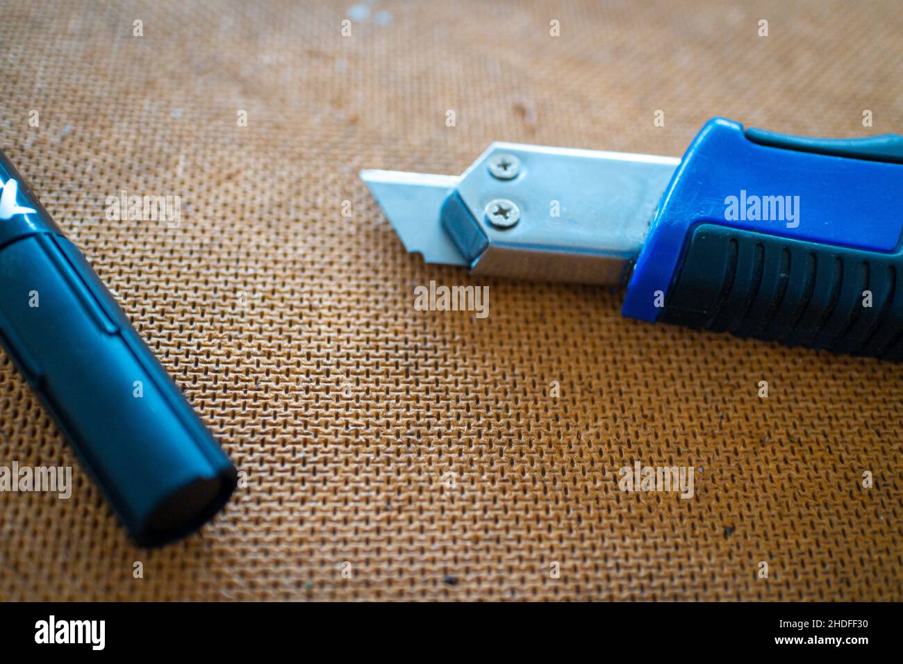 couteau avec poignée bleue et stylo de marquage reposant sur une surface de travail en bois avec un accent sur la plaque en bois Banque D'Images