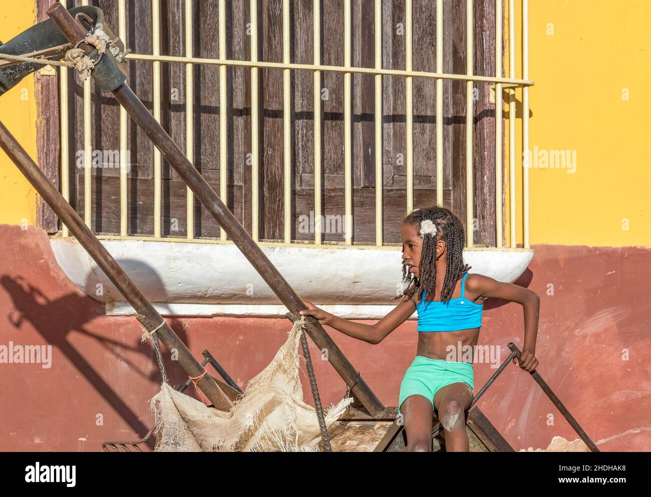 Portrait d'une fille afro-caribéenne jouant dans un chariot stationnaire par l'architecture coloniale à Trinidad.6 janvier 2022 Banque D'Images