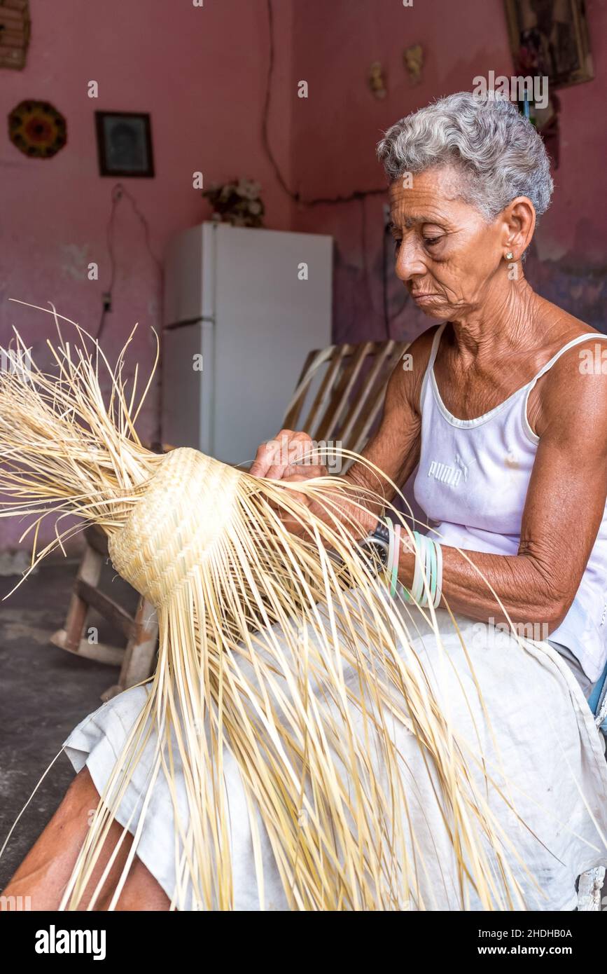 Portrait d'une femme afro-caribéenne senior qui fait un chapeau de paille qui est un souvenir traditionnel.Elle travaille dans le salon de sa maison.6 janvier Banque D'Images