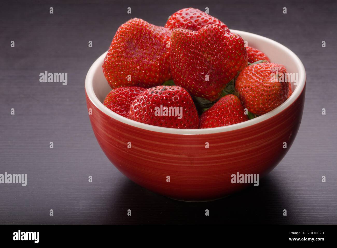 Bol de bouche arroser les fraises mûres rouges sur une surface noire.Fruit de la vie et riche en nutriments et cette saveur spéciale. Banque D'Images