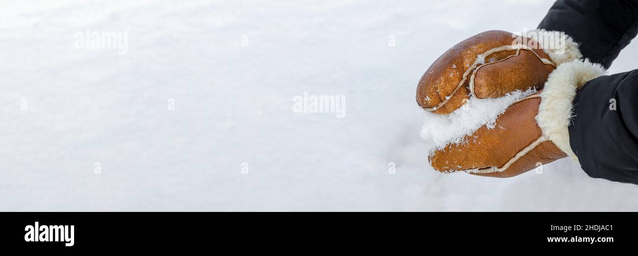 Première neige, faisant des boules de neige dans le parc de près.Les mains des moufles chaudes font de la neige en hiver.Moufles en cuir marron dans la neige en hiver Banque D'Images