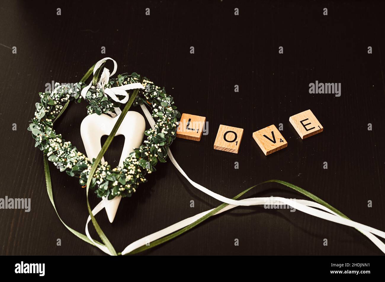 Le mot Love est posé à partir de lettres en bois, à côté d'un coeur blanc sur fond noir Banque D'Images