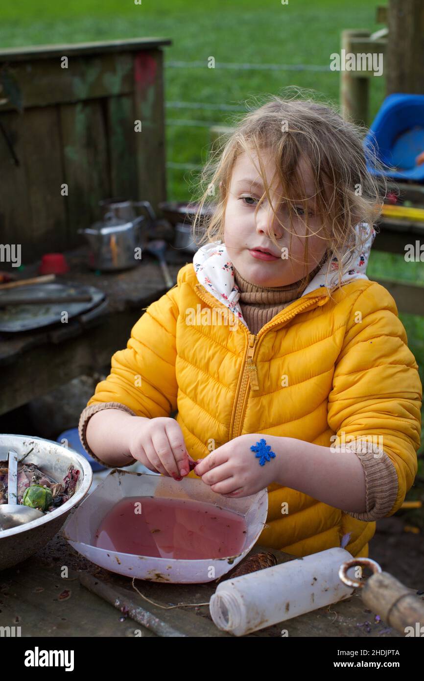 Un enfant de 5 ans jouant à l'extérieur dans une cuisine de boue, Royaume-Uni Banque D'Images