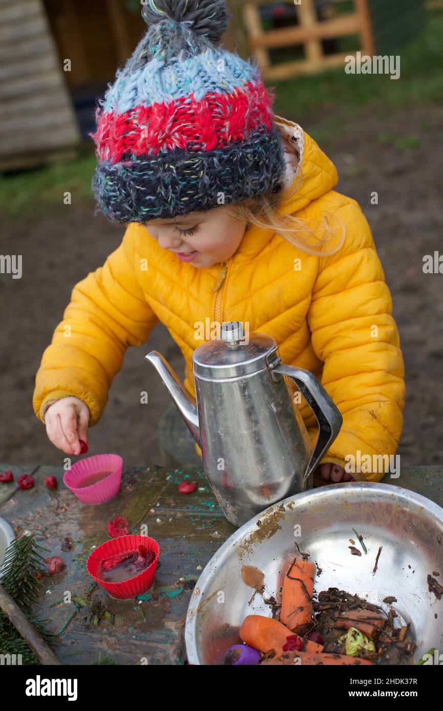 Un enfant de 3 ans jouant à l'extérieur dans une cuisine de boue, Royaume-Uni Banque D'Images