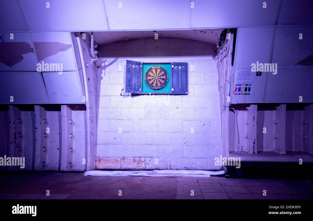 Un vieux jeu de fléchettes, dans un tunnel souterrain, qui a été bien utilisé et est éclairé sur le mur. Banque D'Images