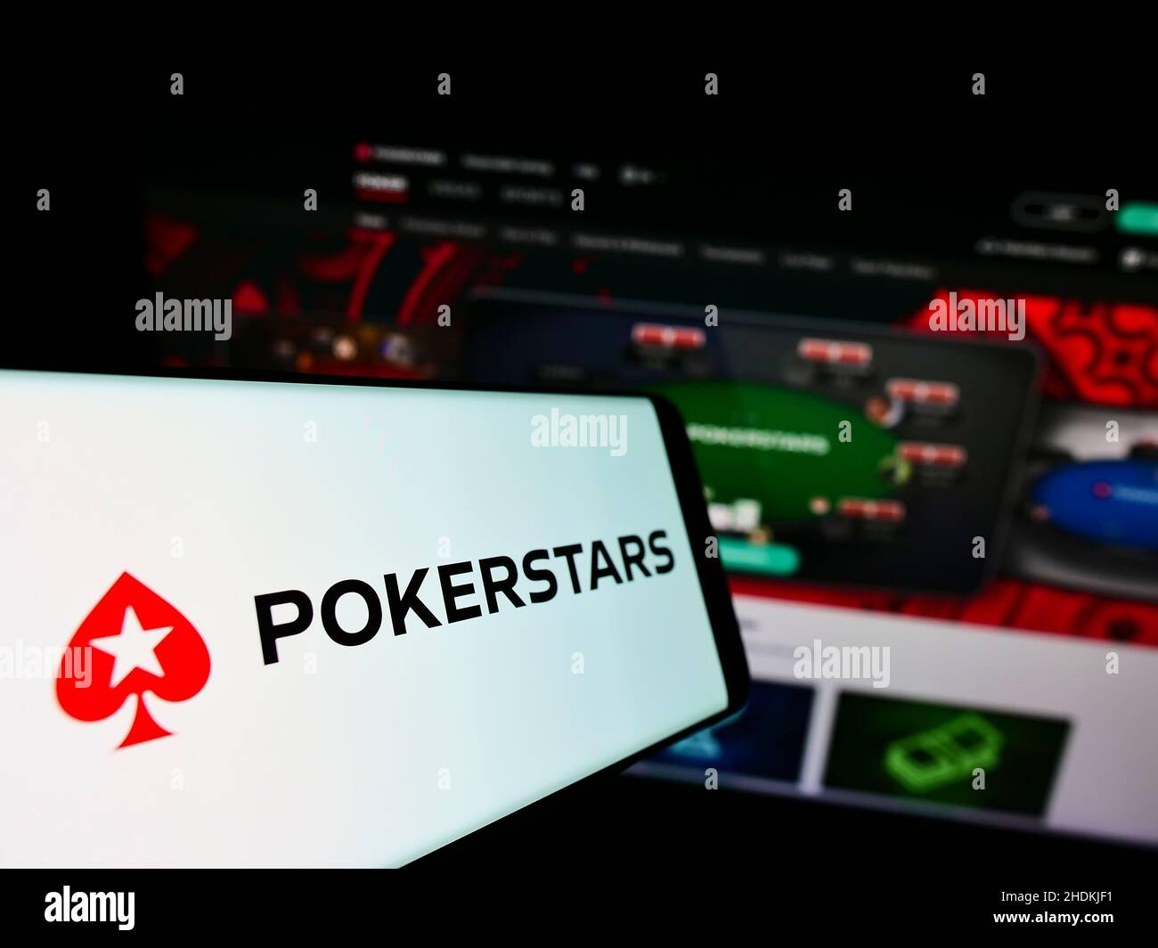 Téléphone portable avec logo de la salle de poker en ligne PokerStars sur l'écran en face du site Web d'affaires.Mise au point au centre-gauche de l'écran du téléphone. Banque D'Images