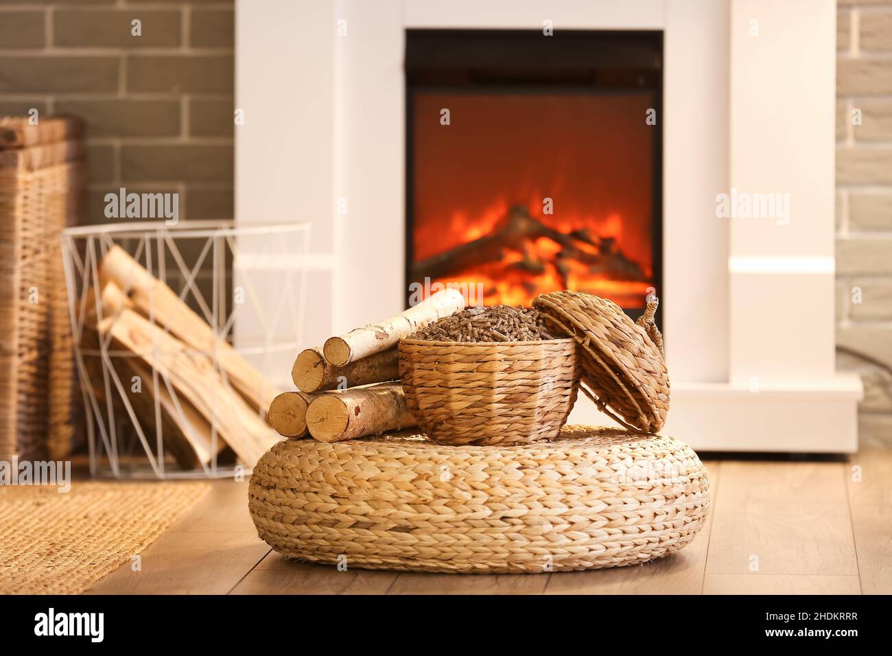 Panier en osier avec granules et bois de chauffage sur pouf dans le salon  Photo Stock - Alamy