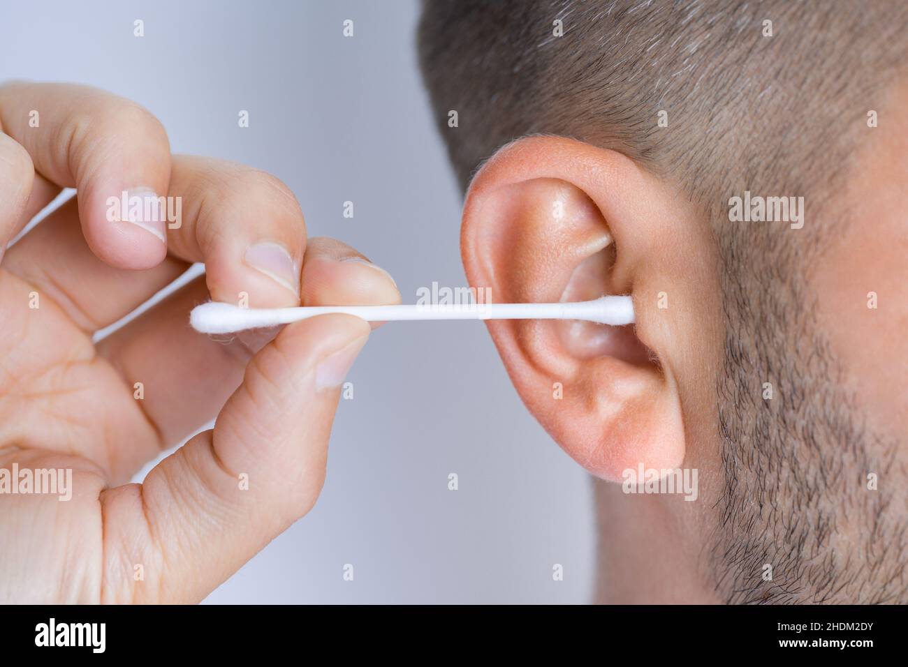 Gros Plan Photo De L'homme Brune Souriant À La Caméra Et Nettoyant Ses  Oreilles Avec Un Coton-tige Isolé Sur Fond Blanc Banque D'Images et Photos  Libres De Droits. Image 130055906