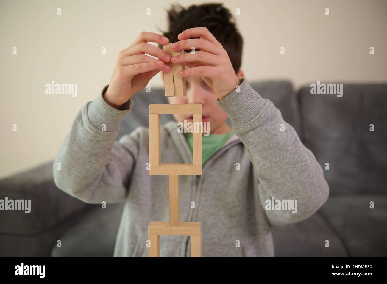 Gros plan sur les mains de garçons d'école de race blanche, perplexes, concentrés sur la construction de structures complexes hautes à partir de blocs de bois.Compétence moteur fine Banque D'Images