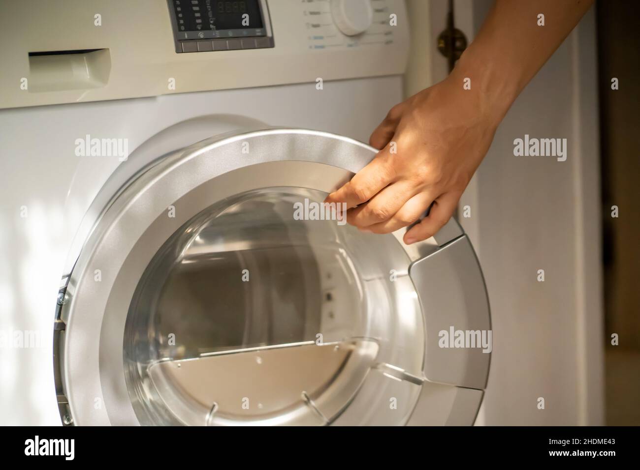 L'homme utilise la machine à laver moderne. Banque D'Images