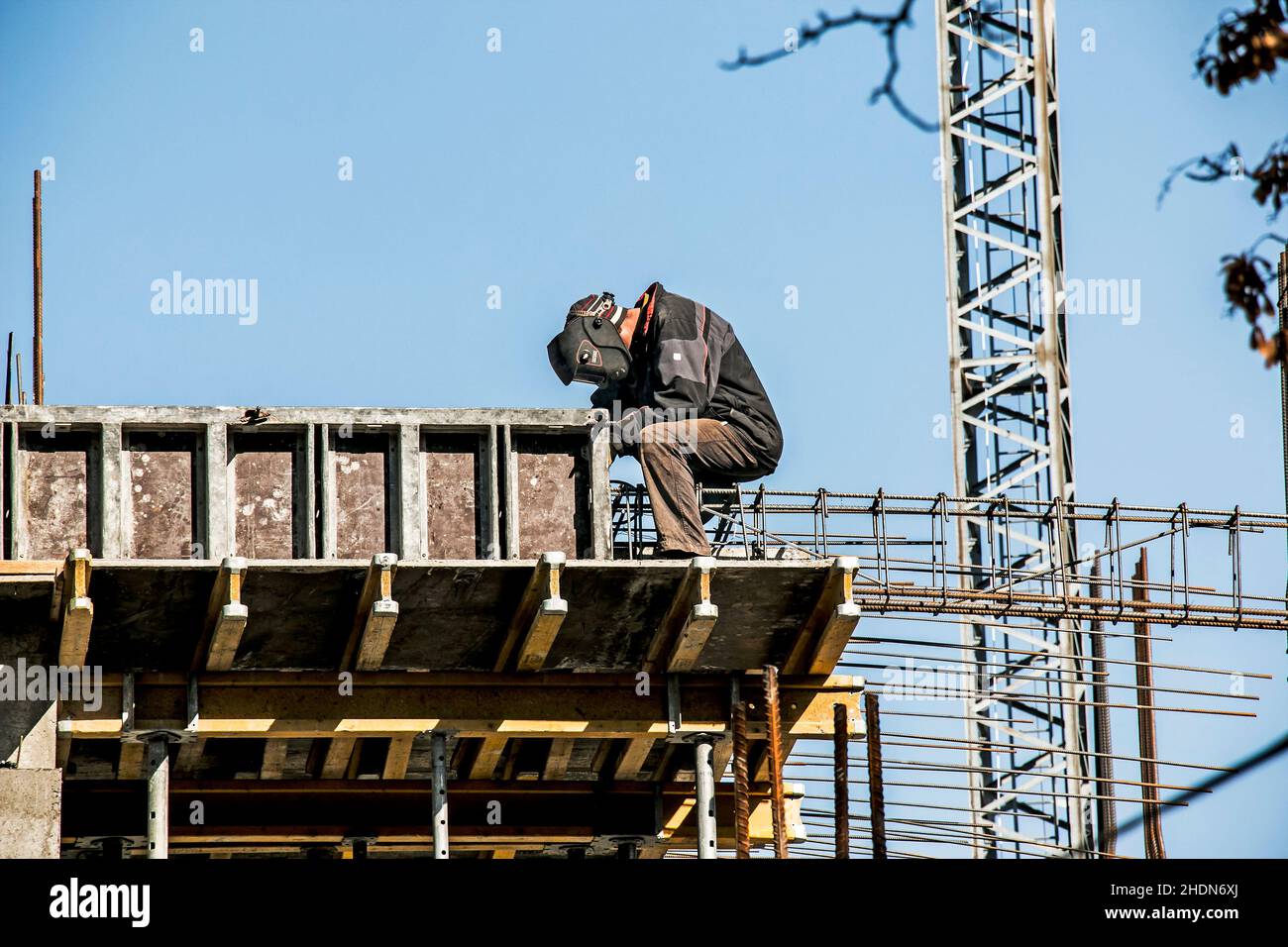 Un soudeur prépare un cadre de renfort pour verser du béton dans la poutre porteuse d'un bâtiment résidentiel. Banque D'Images