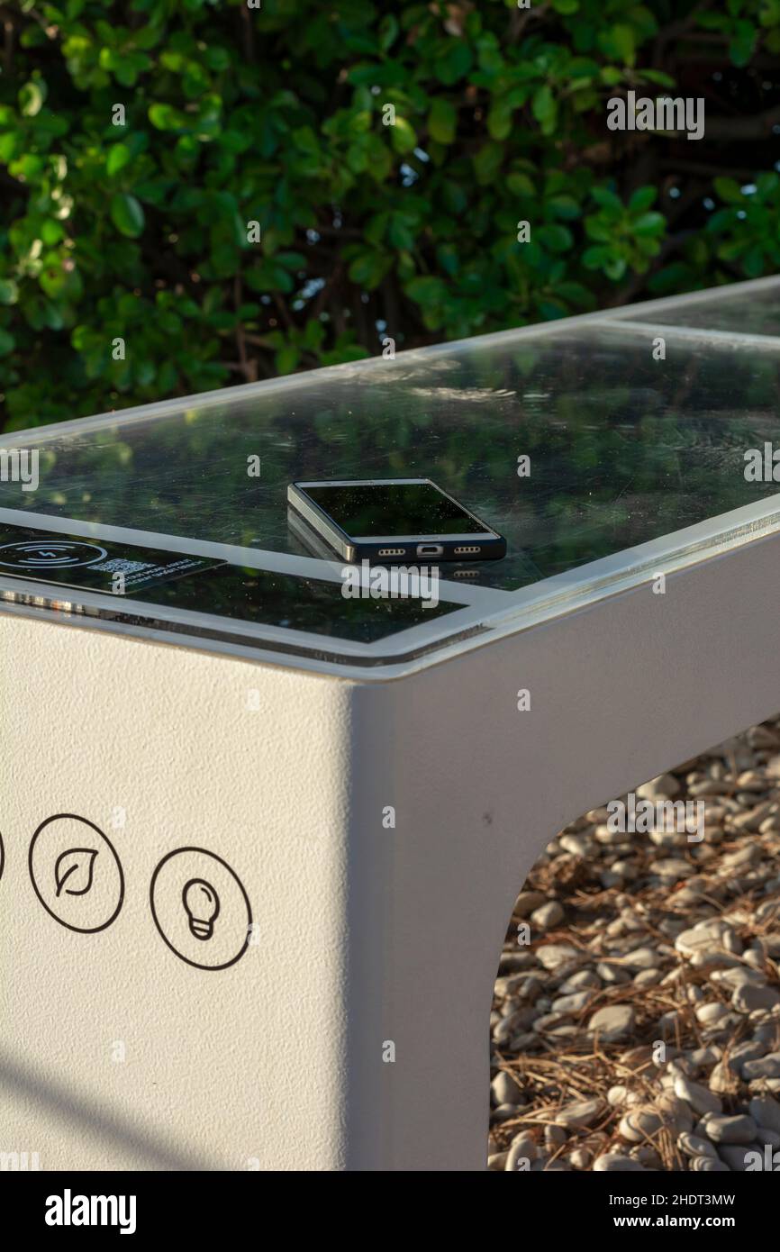 Smart Solar Bench dans les lieux publics, alimenté par la lumière du soleil fournit des charges sans fil et câblées pour les utilisateurs, wi-fi gratuit et capteurs de température et de temps. Banque D'Images