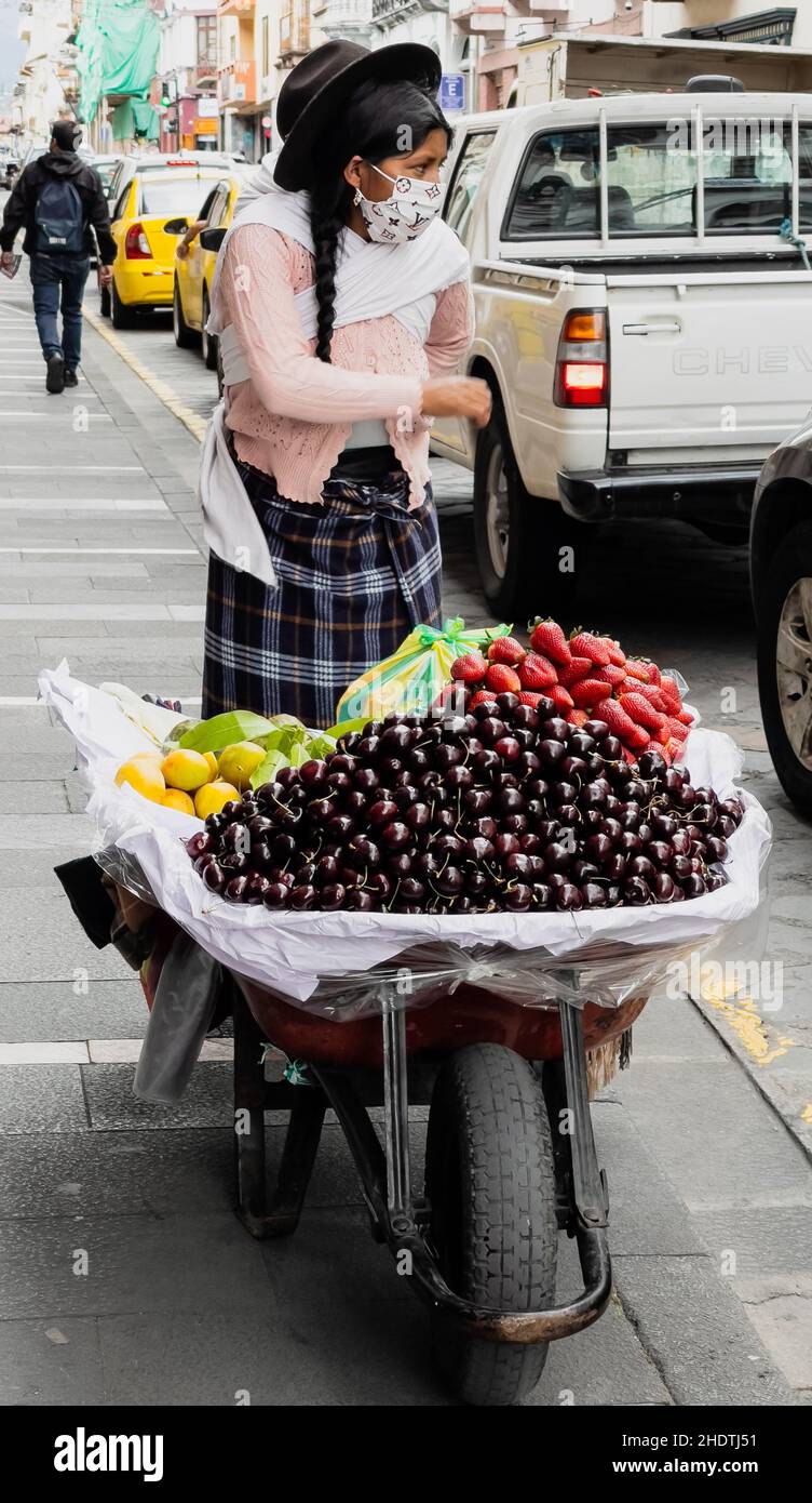 Cuenca, Équateur, 24 décembre 2021 - une femme vend des cerises et des fruits d'une brouette. Banque D'Images