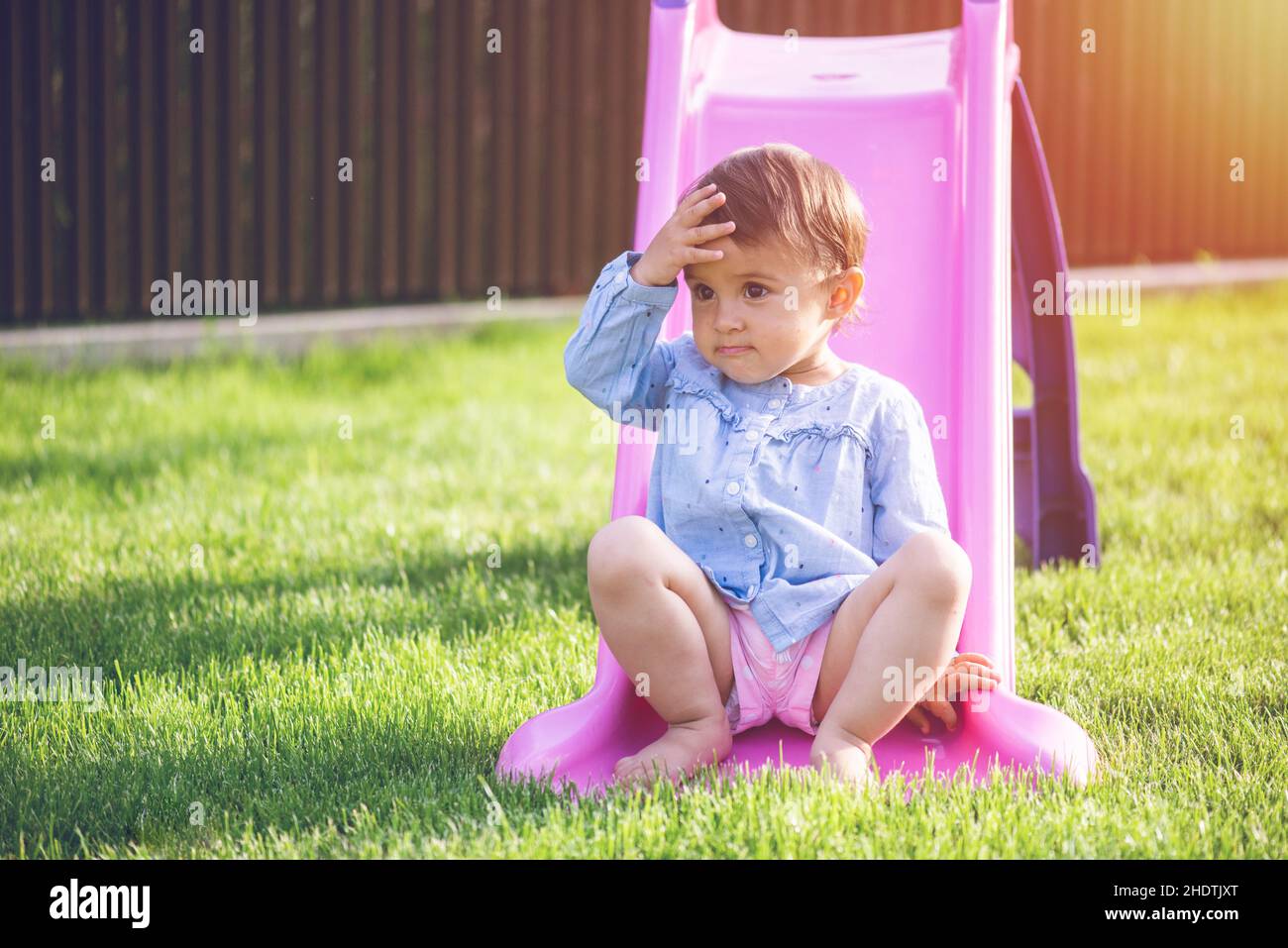 Petite et mignonne fille jouer sur la diapositive et faire une grimace pendant qu'elle joue. Banque D'Images