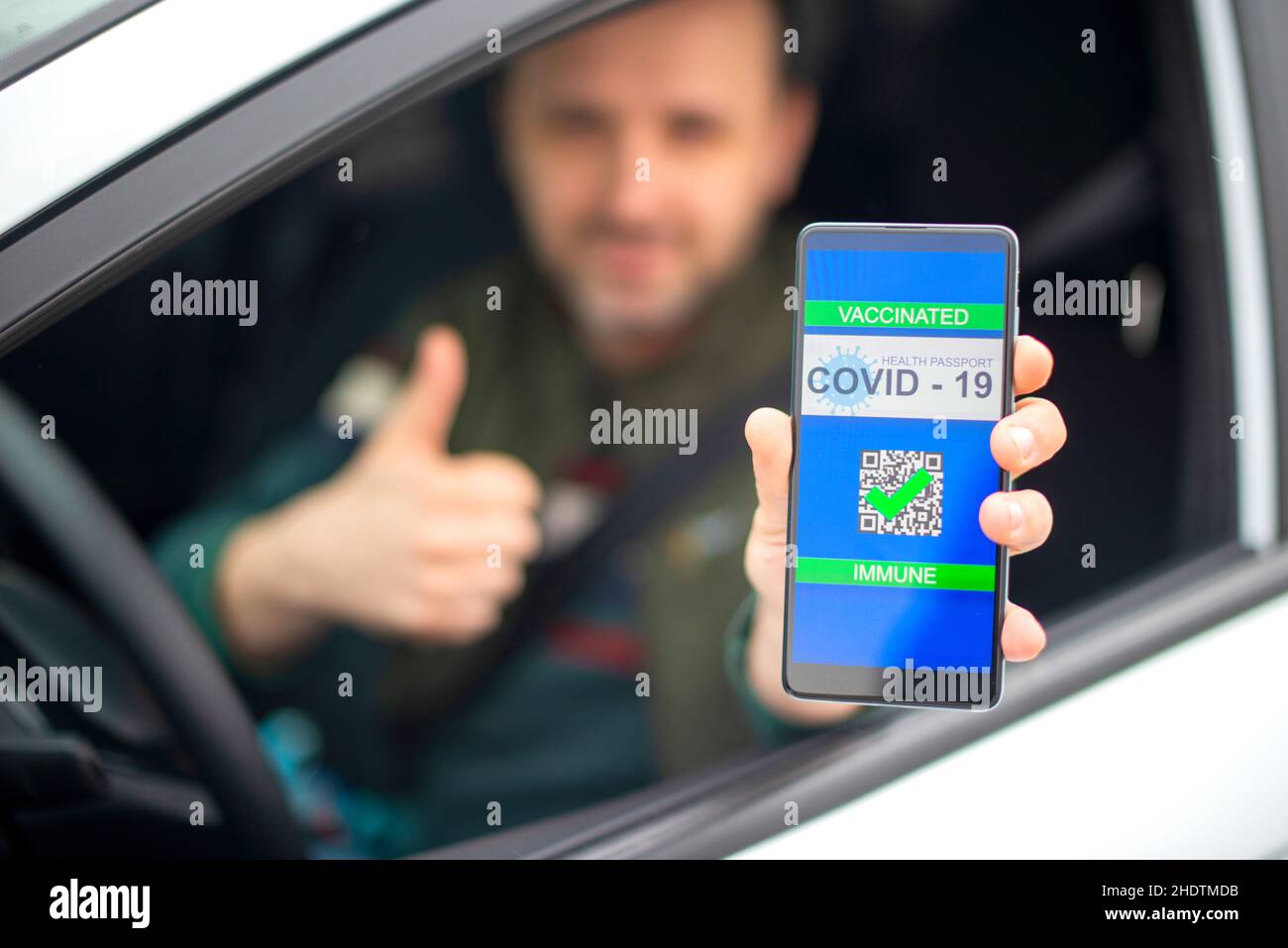 Homme montrant un passeport de vaccin sur son téléphone alors qu'il est dans sa voiture. Banque D'Images
