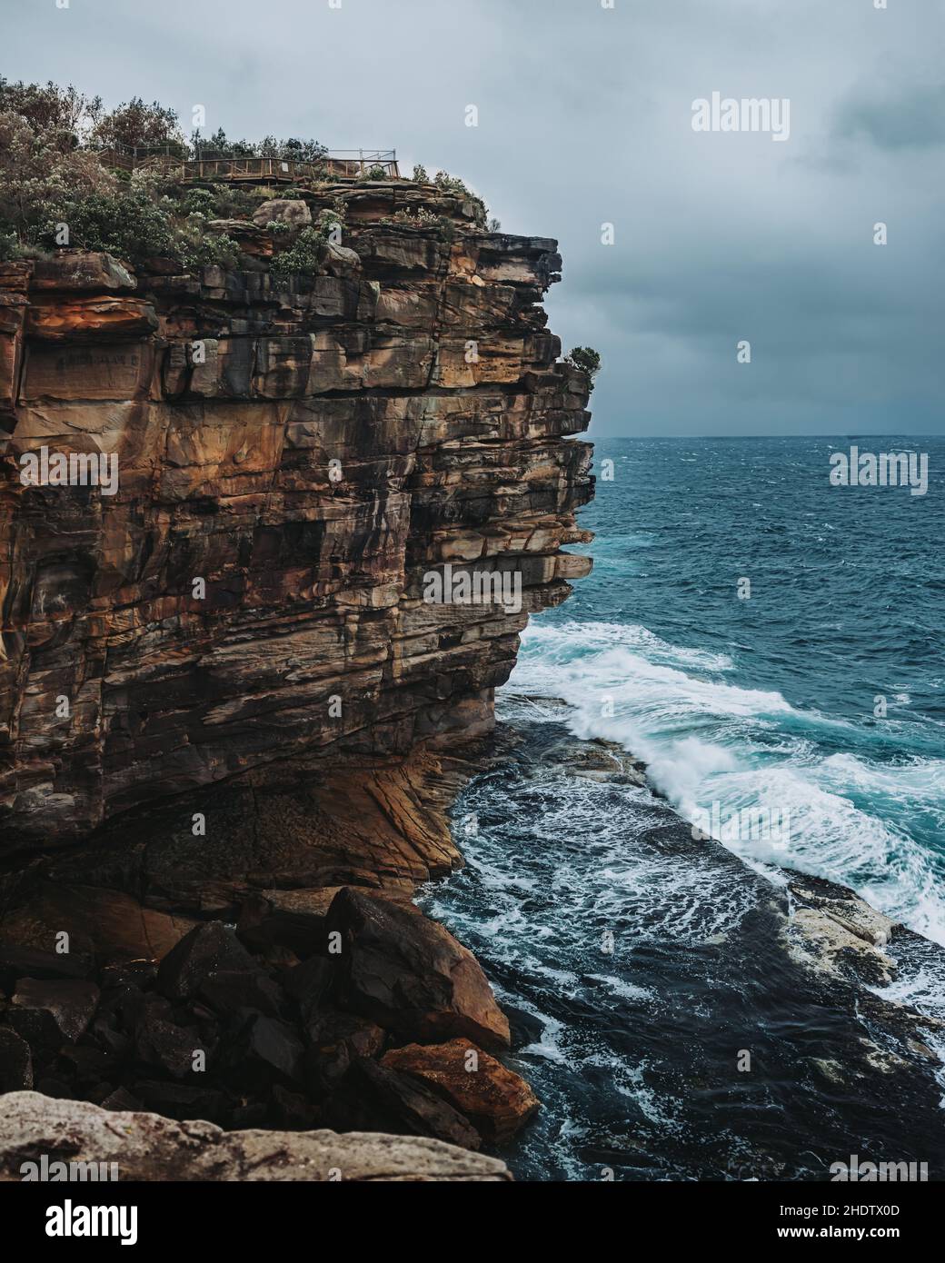 Vue panoramique sur les vagues qui frappent les rochers sous un ciel nuageux dans The Gap à Watson Bay, en Australie Banque D'Images