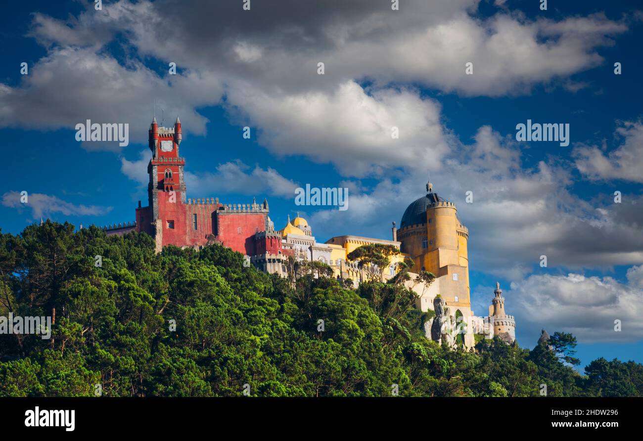 Vue sur le Palais Da Pena dans la ville portugaise de Sintra, au sommet d'une colline, avec un ciel bleu et des nuages blancs. Banque D'Images