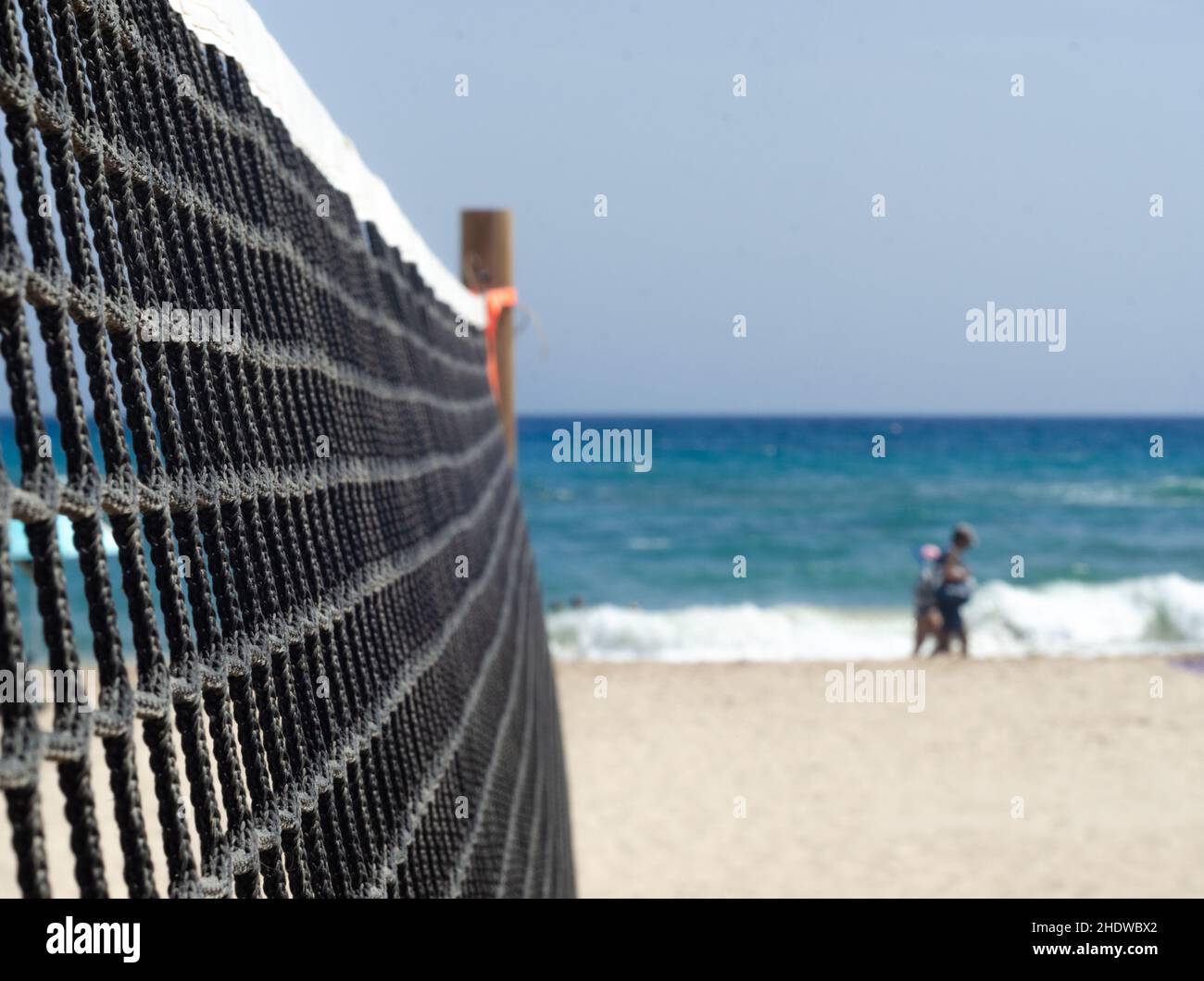 filet de volley-ball sur la plage. terrain de volley vide mais deux personnes méconnues se promènent le long de la plage. mère et fille se promènent sur le sable u. Banque D'Images