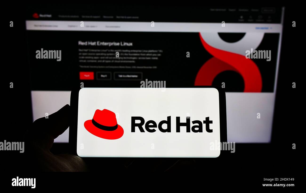 Personne détenant un smartphone portant le logo de la société logicielle américaine Red Hat Inc. À l'écran, devant le site Web.Mise au point sur l'affichage du téléphone. Banque D'Images