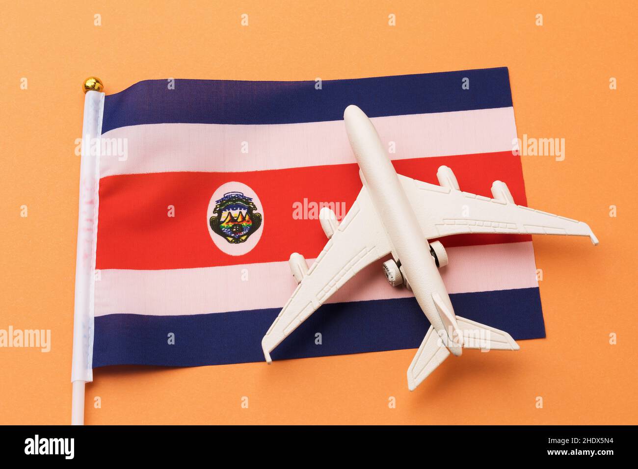 Drapeau et avion jouet sur fond bleu, concept de vol pour le Costa Rica, vue de dessus Banque D'Images