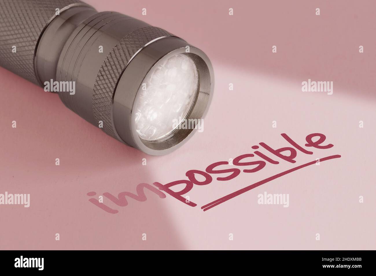 Lampe de poche avec le mot impossible sur fond rose - concept de pensée positive et de changement impossible dans possible Banque D'Images